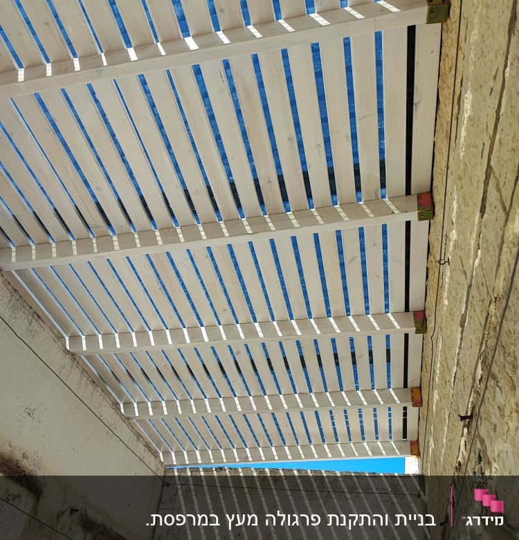 פרגולה מעץ עם קורות לבנות וגג שקוף